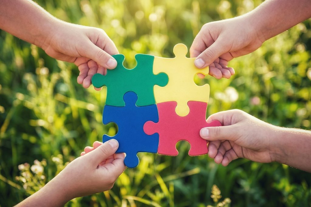 Hands joining colourful puzzle pieces